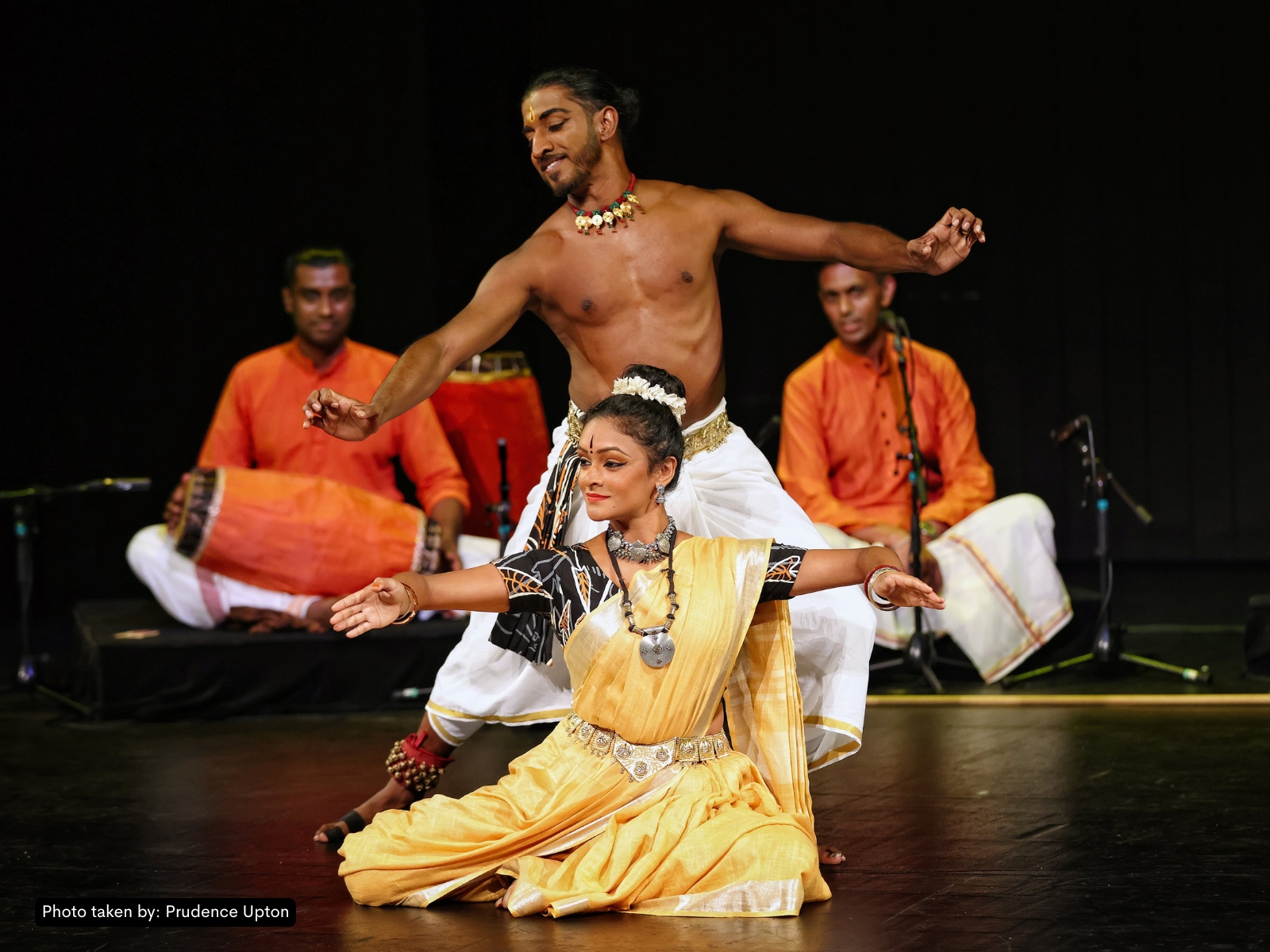 Performance still from Sacred Music Festival 2019 — Kersh mid-Bharatanatyam, full body, natural-toned backdrop.